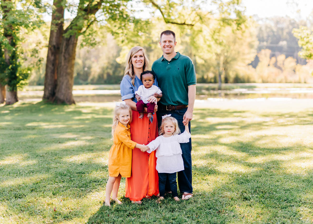 A family undergoing physical therapy poses for a family photo in a park.