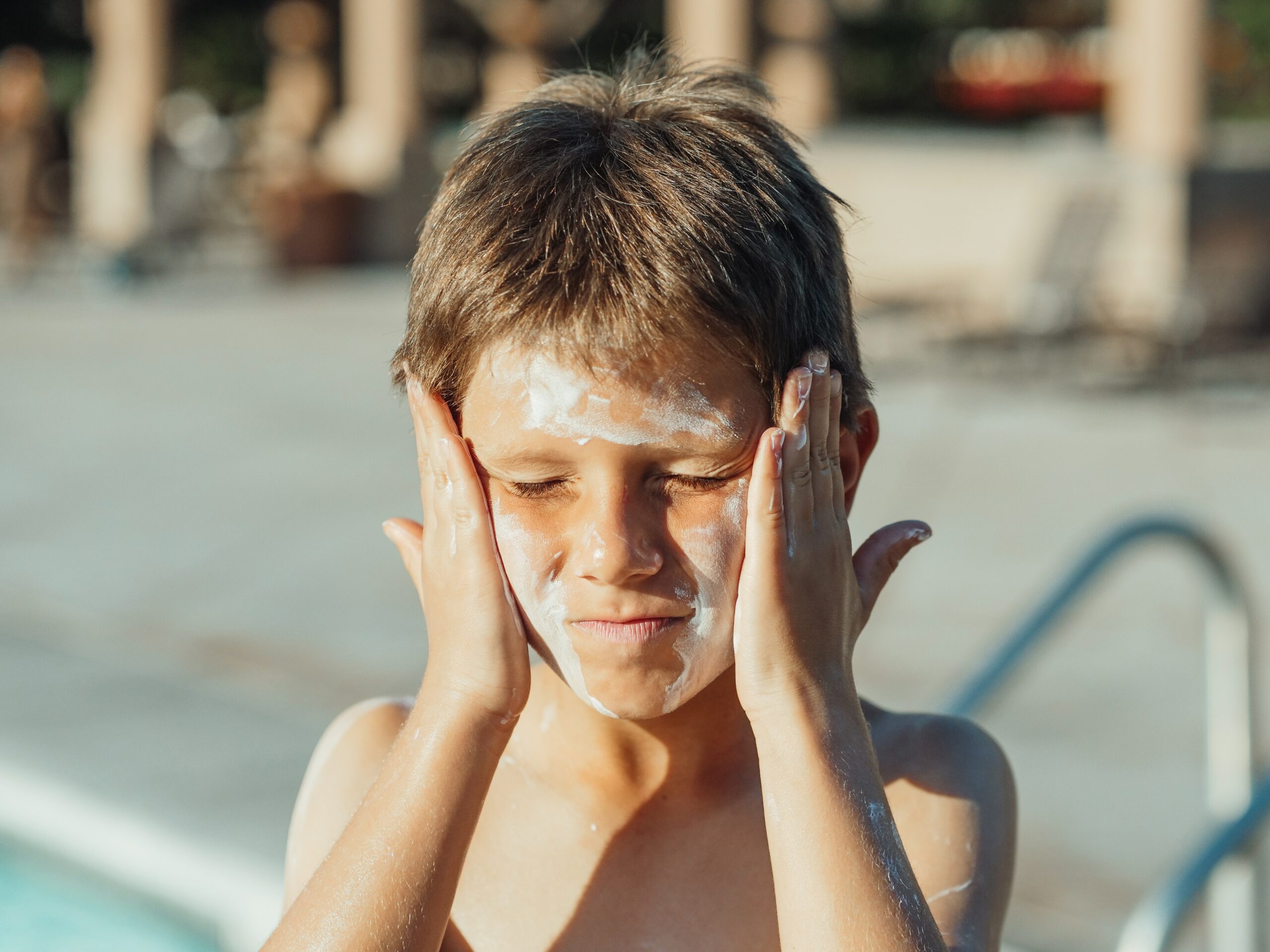 A young boy undergoing physical therapy, with his face covered in sunscreen.